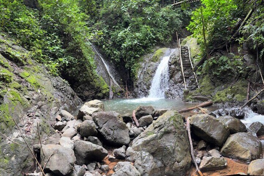 A waterfall in a forested area with rocks and a wooden bridge. 5