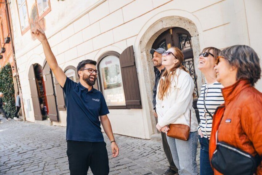 A person pointing towards a building with arched windows and a cobblestone street. 5