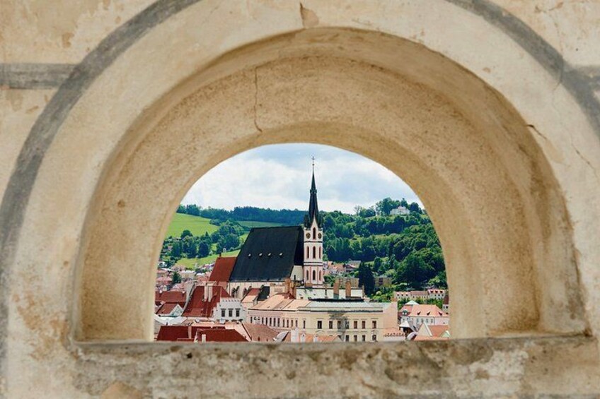 A stone archway framing a view of a town with a prominent church and surrounding buildings. 5
