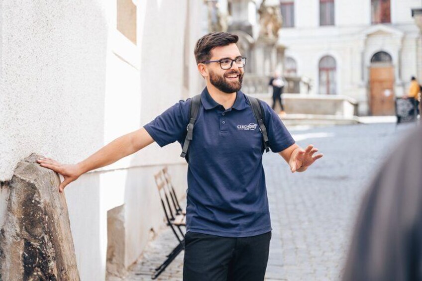 A person in a blue shirt leaning against a wall in a narrow street with buildings in the background. 4