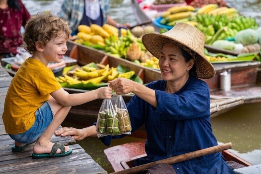 A person in a boat with a child, exchanging items. 5