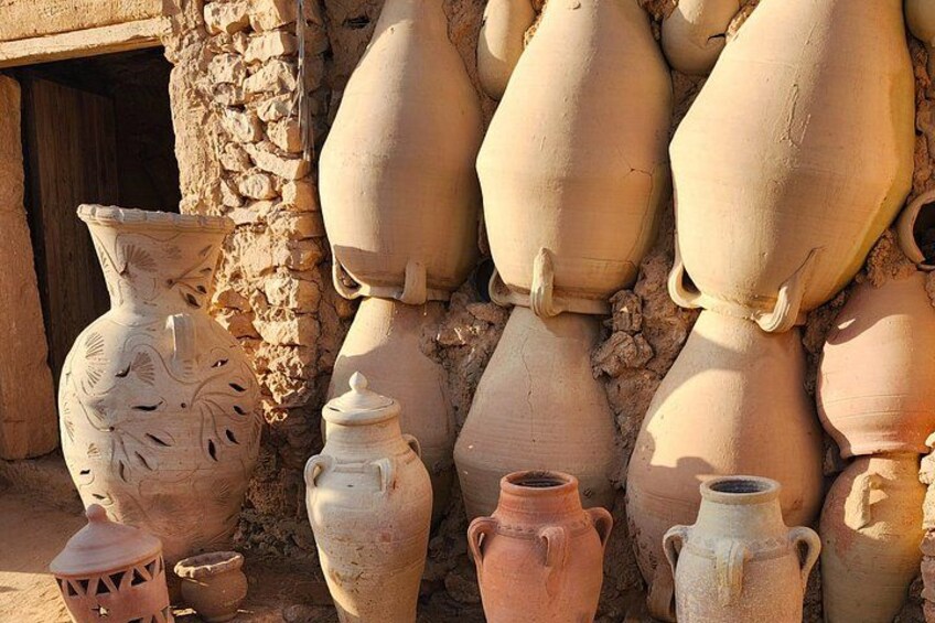 Eine Sammlung antiker Keramik, darunter eine große Vase mit einem geschnitzten Dekor, vor einer Steinwand. 4