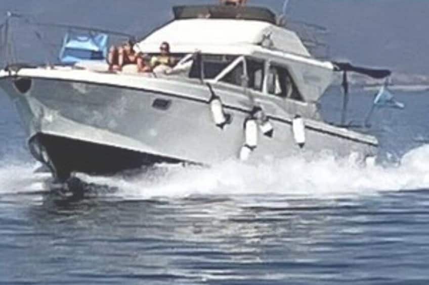 A boat with passengers, moving through water. 1