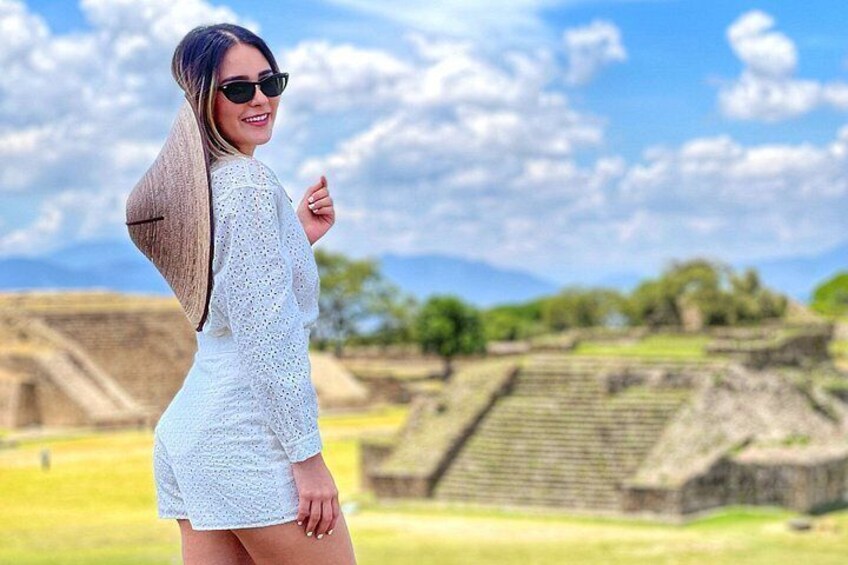 A person in a white dress standing in front of ancient ruins with stepped structures. 1