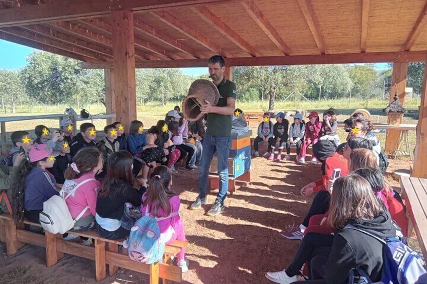 A man speaking to a group of children under a wooden shelter. 4