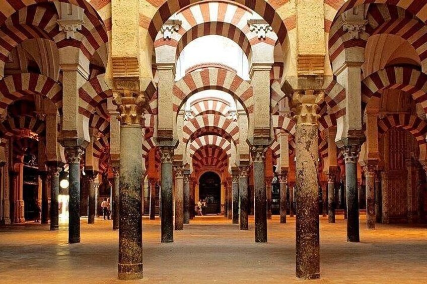A series of arches with alternating red and white voussoirs, a central open space, and columns with capitals. 1