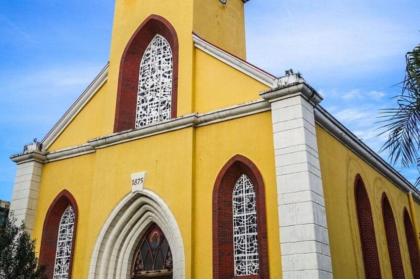 A yellow church with arched windows and a clock tower, marked with the year 1875. 5