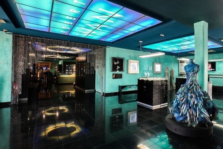 A modern lobby with a reflective floor, a mannequin in a dress, and a neon-lit ceiling. 1