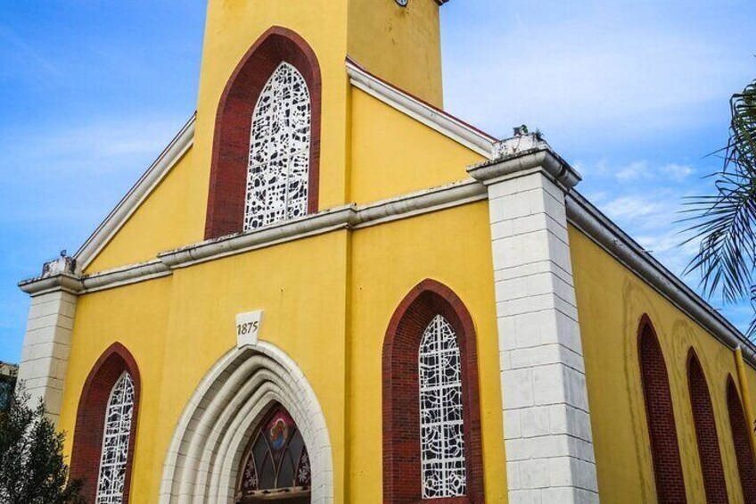 A yellow church with arched windows and a clock tower. 5