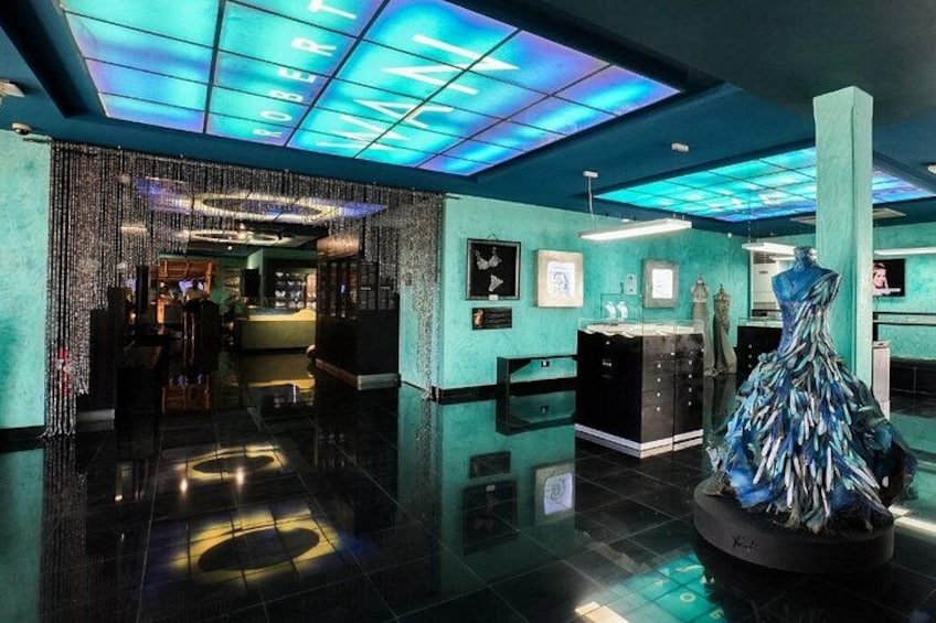 A modern interior with a teal color scheme, a reflective floor, and a central sculpture. 1