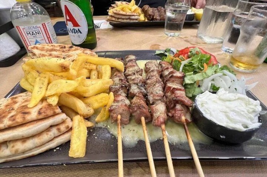 A meal with kebabs, fries, flatbread, salad, and a bowl of sauce. 3