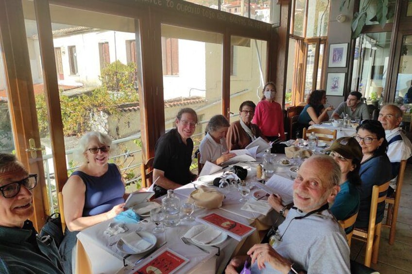 A group of people dining at an outdoor restaurant with large windows and a view of buildings and trees. 5