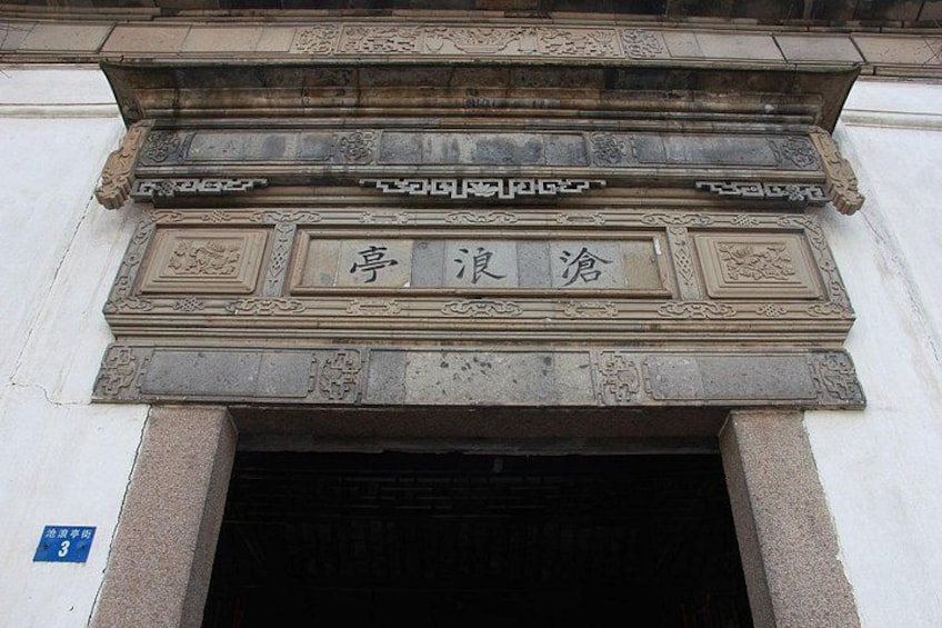 A stone entrance with carved Chinese characters and a blue sign with the number 3. 1