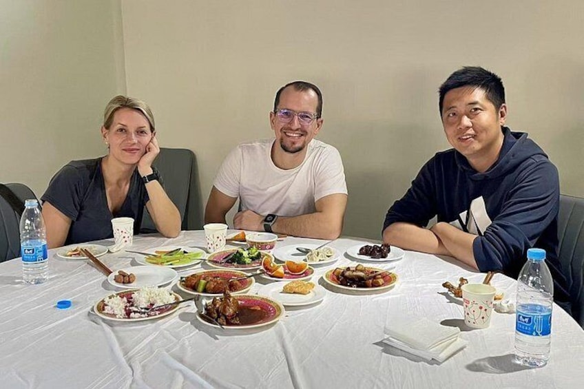 Three people seated at a table with various dishes and drinks. 3