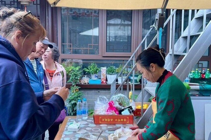 A street food vendor preparing food at a stall with a window and plants in the background. 4