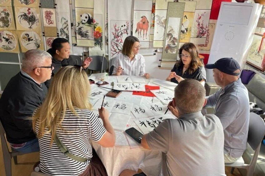 A group of people sitting around a table with Chinese calligraphy and paintings. 2
