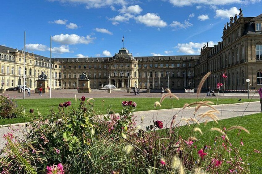 A historic building with a large courtyard, surrounded by well-maintained lawns and flowering plants. 1