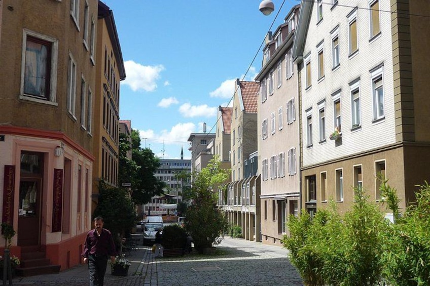 A cobblestone street lined with historic buildings, a person walking, and a clear blue sky. 3