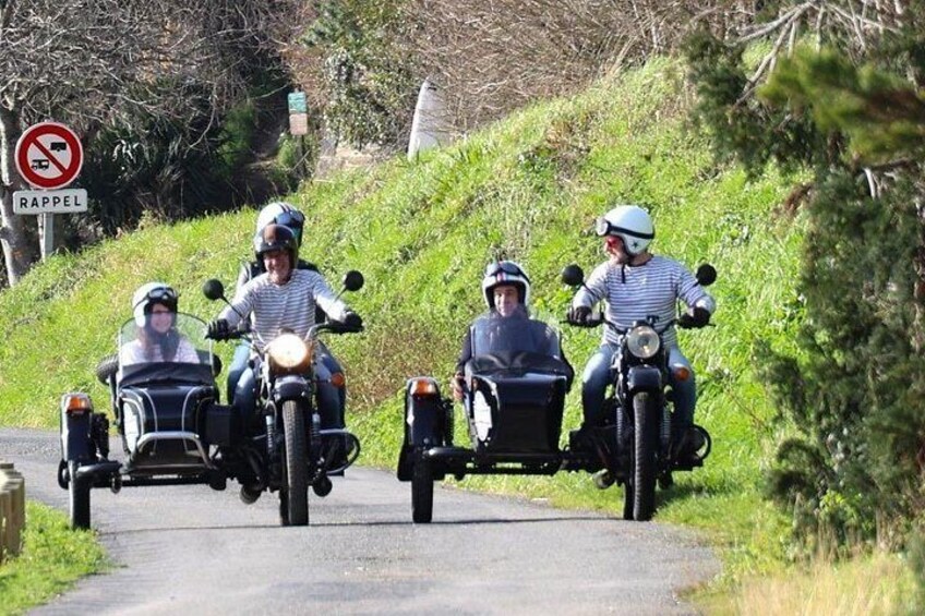 A group of motorcyclists riding on a paved road with a sign indicating a no parking zone. 5