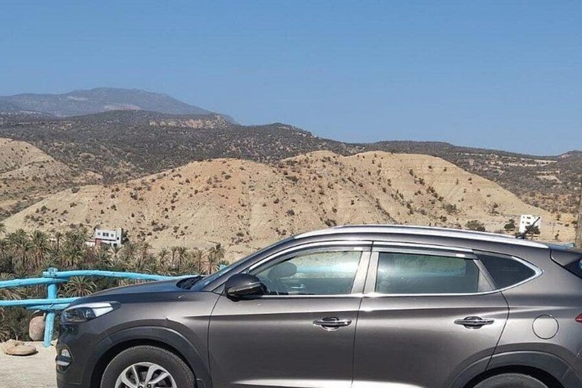 A gray SUV parked with a mountainous landscape in the background. 4