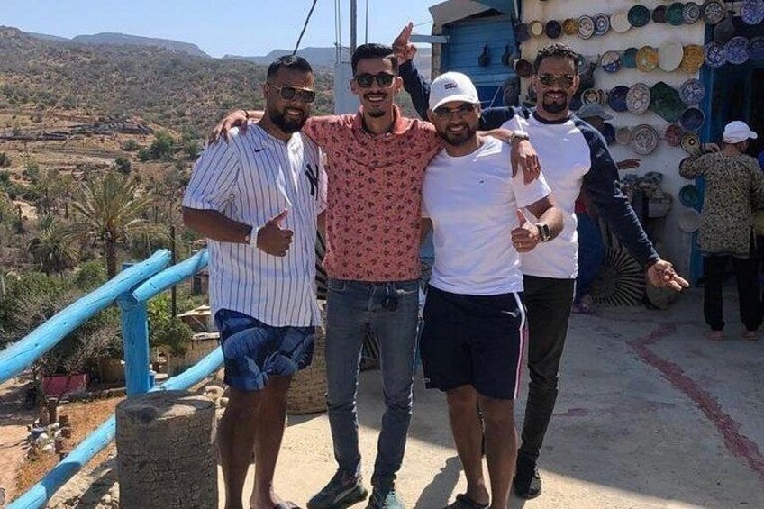 A group of people standing on a concrete platform with a blue railing, overlooking a hilly landscape. 3