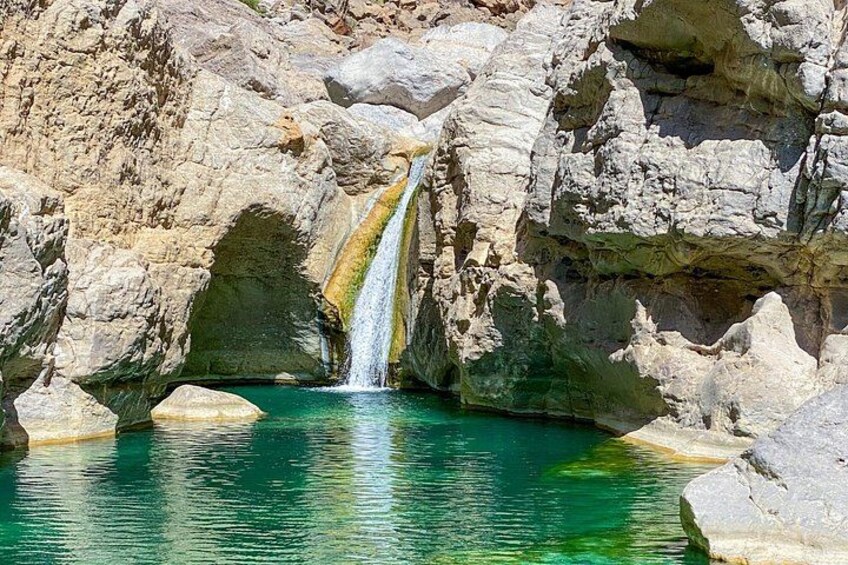 Ein Wasserfall stürzt in einen türkisblauen Pool zwischen felsigen Klippen. 4