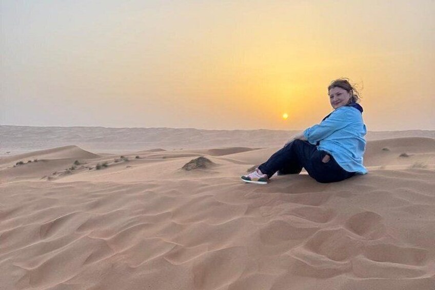 Eine Person sitzt auf Dünen bei Sonnenuntergang. 2