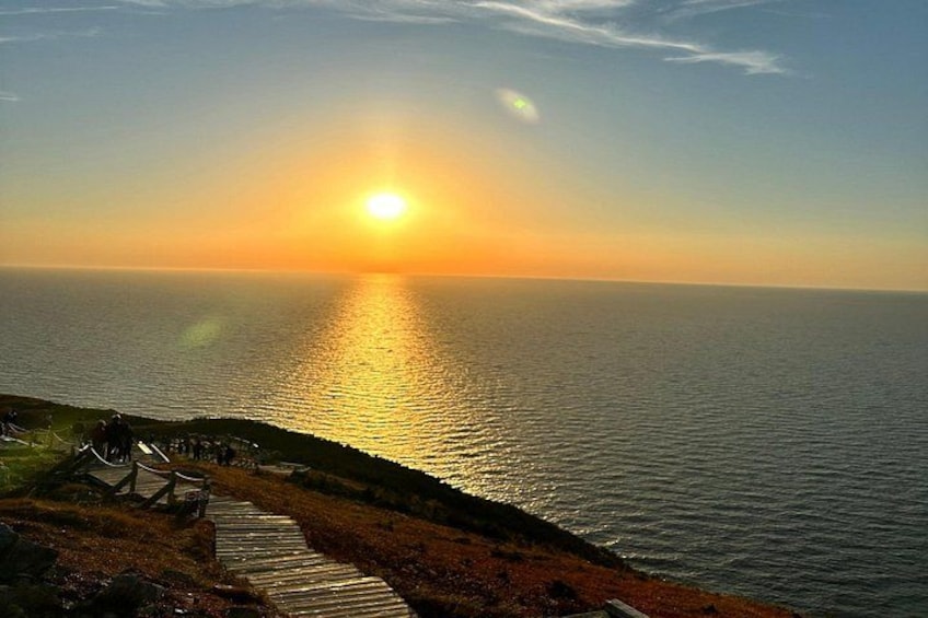 Un atardecer sobre el océano con una pasarela de madera que conduce al agua. 1