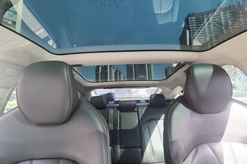 The interior of a car with black leather seats and a sunroof. 2