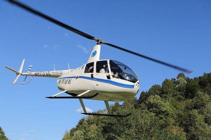 A helicopter flying over a forested area. 2