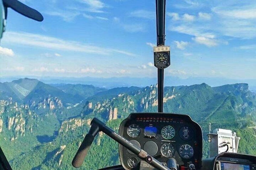 A helicopter cockpit with a mountainous landscape in the background. 5