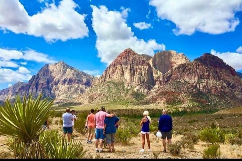Un grupo de personas sobre un terreno arenoso, con un paisaje montañoso al fondo. 1