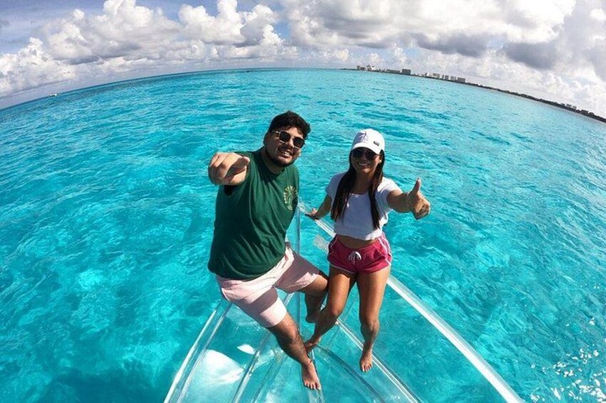 Two people on a boat in clear blue water with a distant shoreline. 5