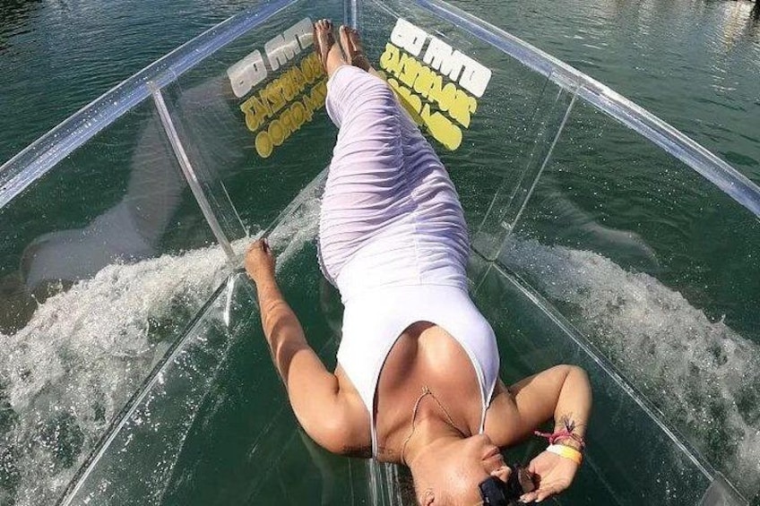 A person lying on a transparent surface in water, wearing a white top and shorts. 3