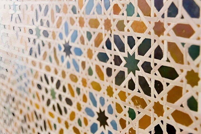 A close-up of a colorful mosaic with geometric patterns and star shapes. 5