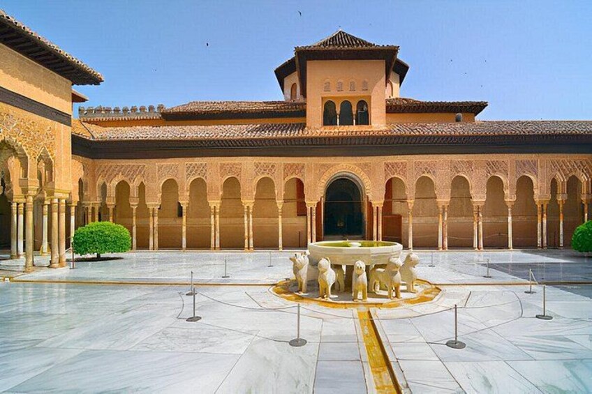 A courtyard with arches, a fountain, and a building with a tiled roof. 2