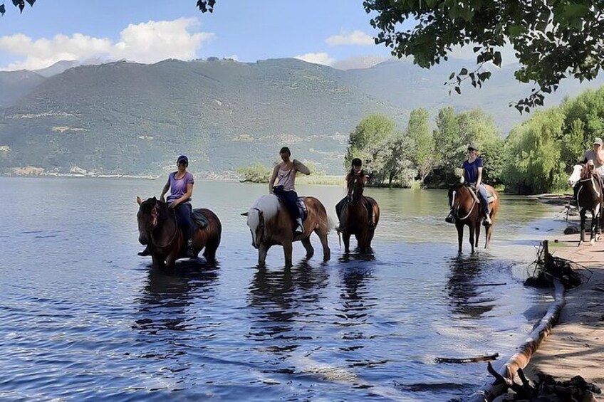 Personas montando a caballo por un río. 1
