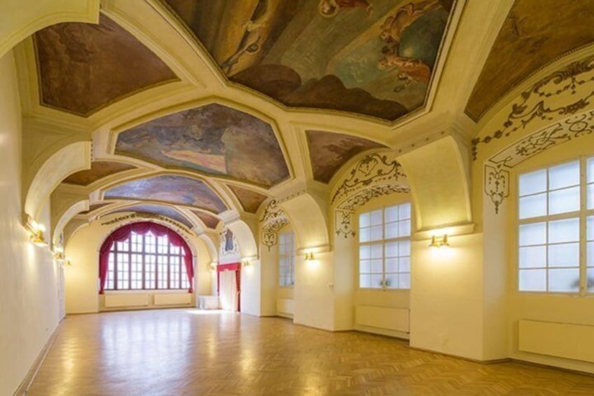 An interior with arched ceilings, large windows, and wall sconces. 5