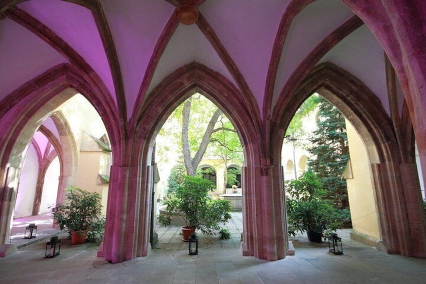 A cloister with arches and potted plants. 4