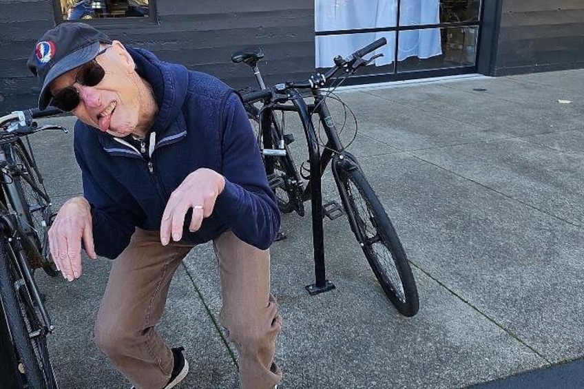 A person crouching next to a bicycle on a sidewalk. 2