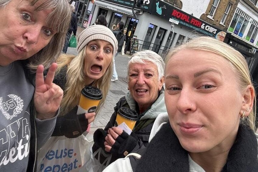 A group of people standing on a street with shops in the background. 1