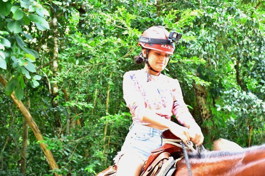 En person som rider på en häst i ett skogsområde. 5