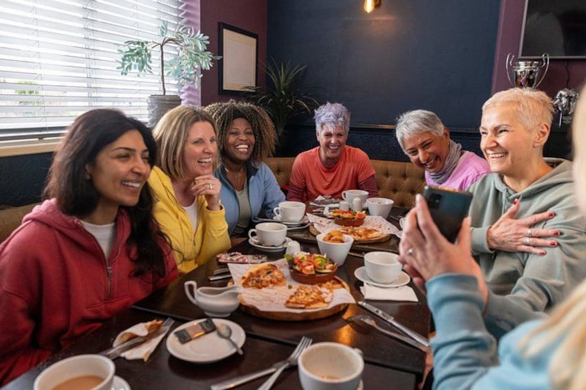 A group of people sitting around a table with food and drinks, engaged in conversation. 2