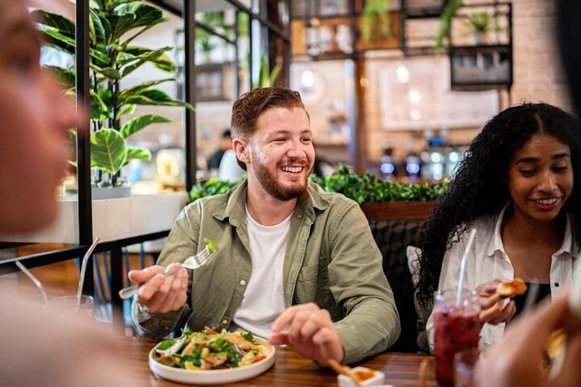 People dining at a restaurant with a modern interior, including plants and shelves with items. 3