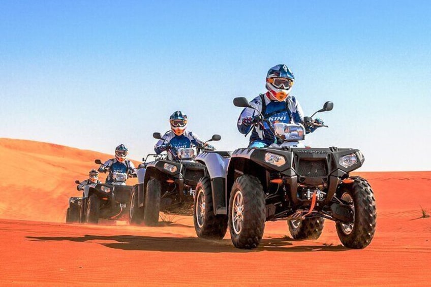 Four riders on quad bikes in a desert landscape. 1