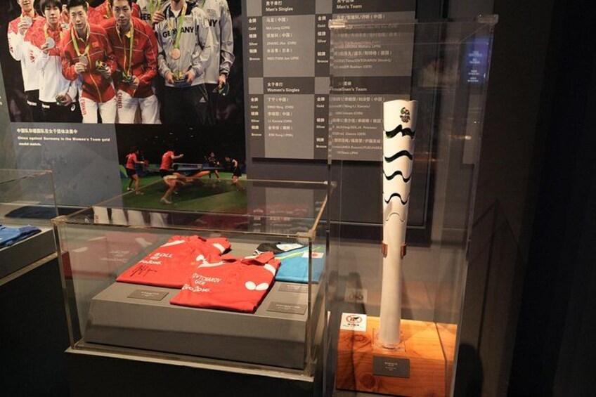 A display case with a ping pong table, a trophy, and a framed photo of a team. 3