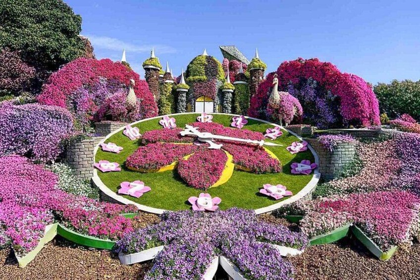 A meticulously landscaped garden with a central circular flower bed, surrounded by various flower arrangements and topiary sculptures. 5