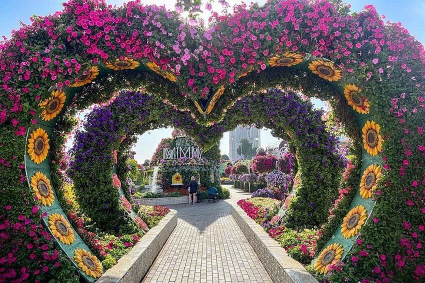 A heart-shaped floral archway with sunflowers and pink flowers, leading to a building labeled 'IMAX.' 1