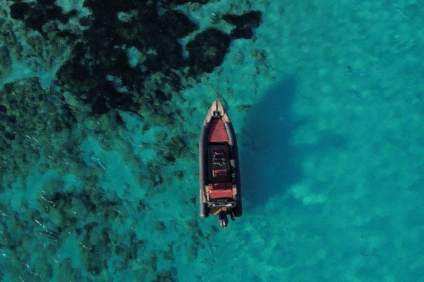 A boat on clear turquoise water with rocky seabed. 1