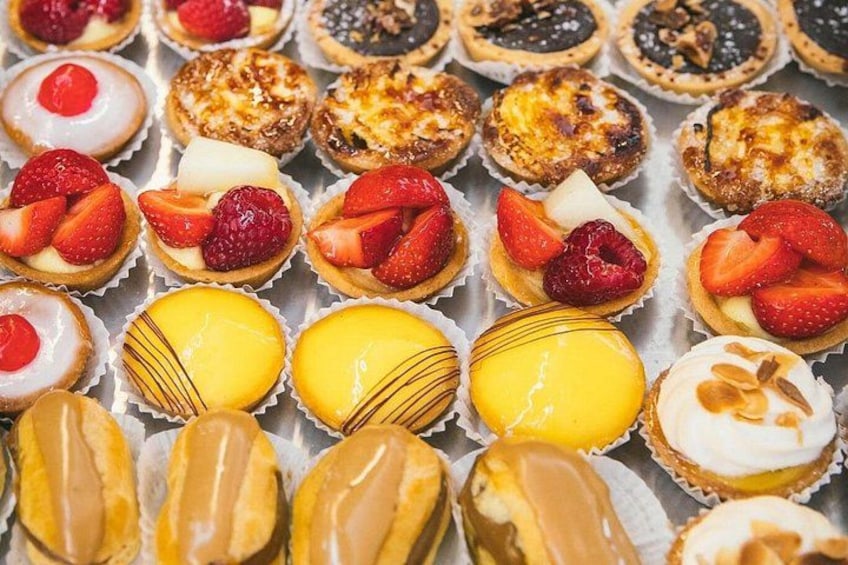 A variety of pastries in paper cups, some topped with strawberries and others with different fillings. 3